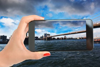 Kadın el smartphone ile fotoğraf çekimi ile Brooklyn Köprüsü, New York üzerinden görüntülemek
