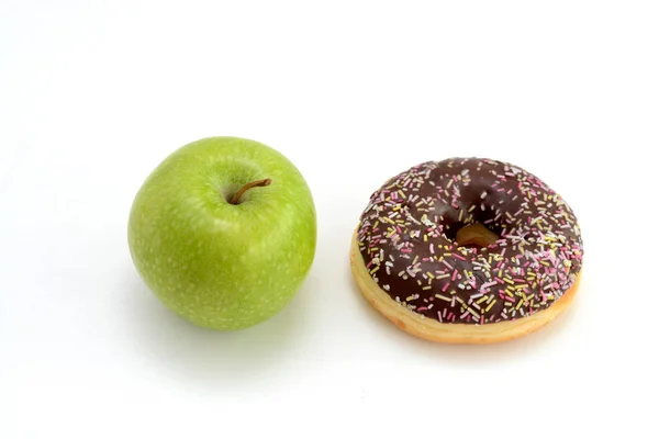 Close-up van lekkere chocolade donut en verse groene appel op witte achtergrond suggereren gezond eten concept — Stockfoto