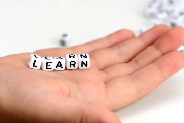 Close-up of child hand holding learn word from tiled letters — Stock Photo, Image