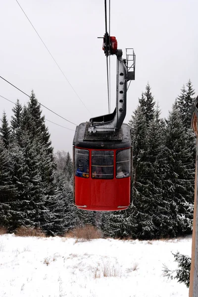 Röd kabel bil stuga med snö tallar och berg i bakgrunden — Stockfoto