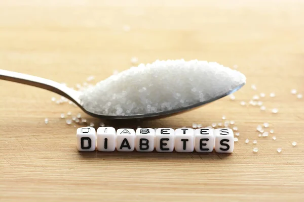 Cuentas de letras de plástico deletreando diabetes en una cuchara llena de azúcar — Foto de Stock