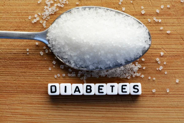Бусины из пластмассы написание диабета в ложке, полной сахара — стоковое фото