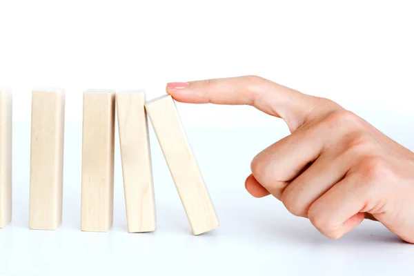 Kadın el bir domino etkisi başlatmak için bir ahşap blok bastırıyor — Stok fotoğraf