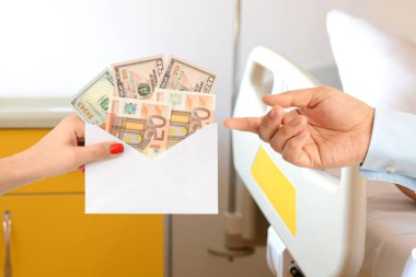 Bozuk bir sağlık sistemi düşündüren bir hastane yatağında para dolu bir zarf ile bir adam rüşvet kadın