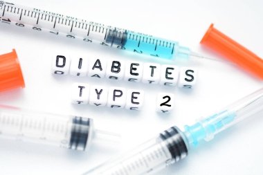 Type 2 diabetes text spelled with plastic letter beads placed next to an insulin syringe clipart