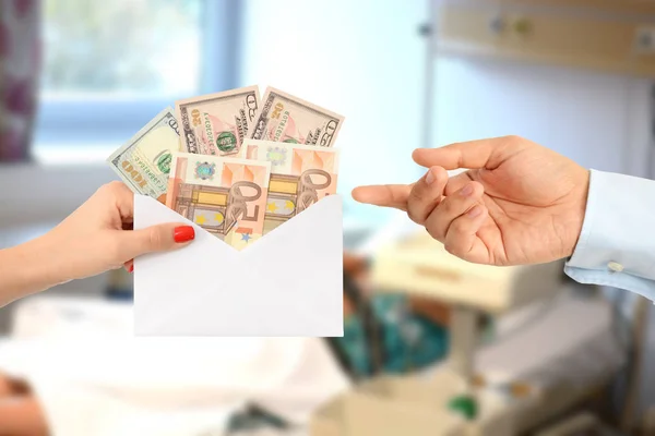 Femme corrompant un homme avec une enveloppe pleine d'argent dans un immeuble de bureaux suggérant un système corrompu — Photo