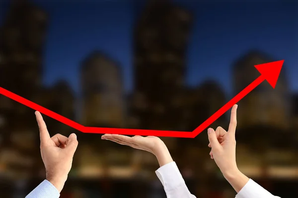 Team of business people working together for economic growth, supporting  with their hands an arrow graph chart going upwards on a blurred urban background — Stock Photo, Image