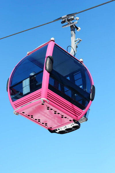 Pink cable car cabin over the snow mountain peak