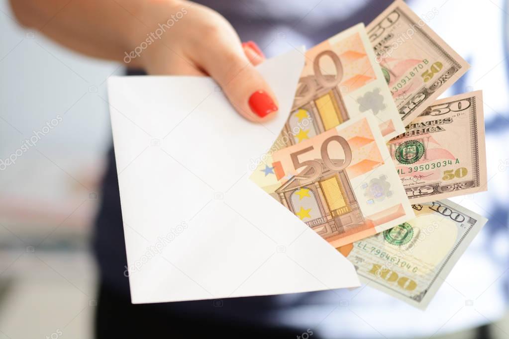 Woman hand holding an envelope full of money, bribing concept