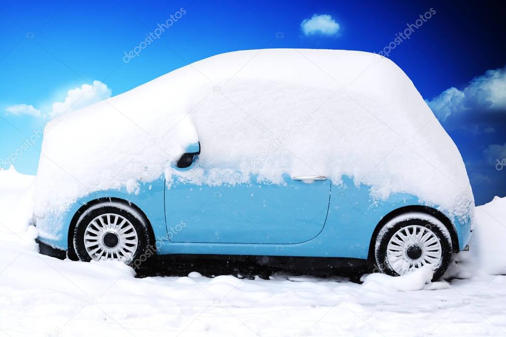 Blue car covered and surrounded by snow drifts after a snow storm 