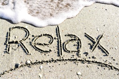 Kum deniz kenarında üzerinde el yazısı kelime sakin ol