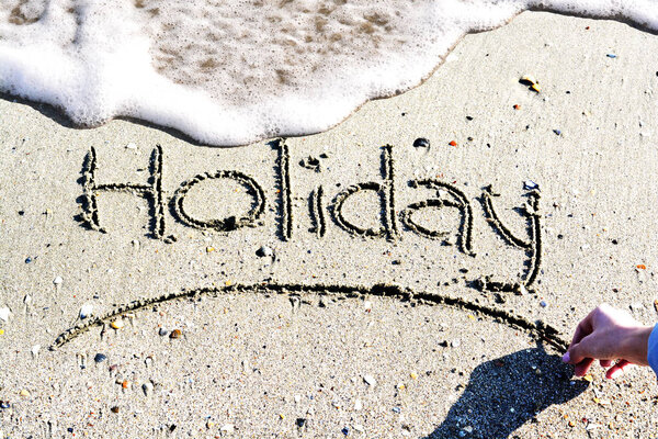 Holiday word handwritten on seamless light colored sand 