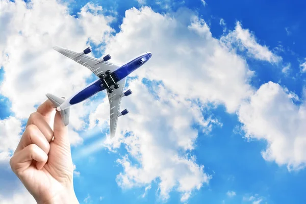 Frau Hand hält ein Flugzeug auf blauem Himmel Hintergrund, Reisekonzept — Stockfoto