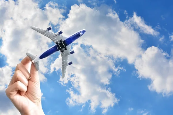 Woman hand holding a plane on blue sky background, traveling concept — Stock Photo, Image
