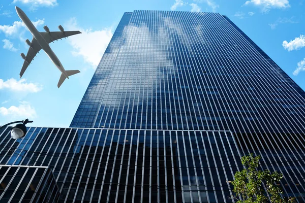 Εμπορικό αεροσκάφος κατά τη διάρκεια πτήσης πάνω από την πόλη, κοντά σε ένα γυάλινο κτίριο — Φωτογραφία Αρχείου