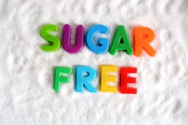 Texto sin azúcar con letras multicolores sobre fondo de azúcar — Foto de Stock