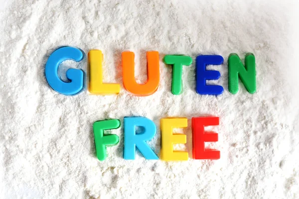 Texto sin gluten deletreado con letras de colores en harina blanca — Foto de Stock