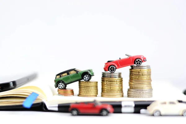 Automotive industry evolution concept with colored toy cars on pile of coins — Stock Photo, Image