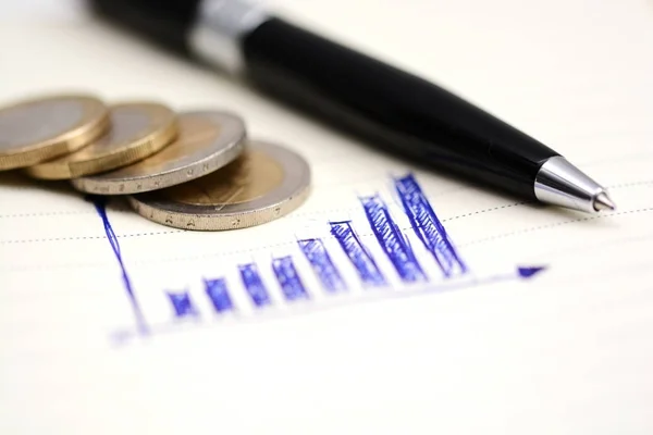 Gráfico de barras ascendente en cuaderno con monedas y herramientas de oficina — Foto de Stock