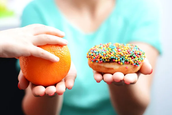 Εκπαίδευση των παιδιών να επιλέγουν υγιεινά τρόφιμα έννοια με μικρή επιλογή κορίτσι να φάνε φρούτα, όχι ένα ντόνατ — Φωτογραφία Αρχείου