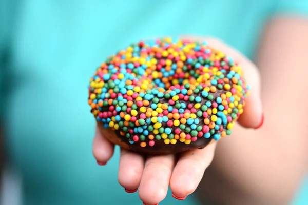 女性の手で色とりどりの食欲をそそるドーナツ カロリー爆弾シンボル — ストック写真
