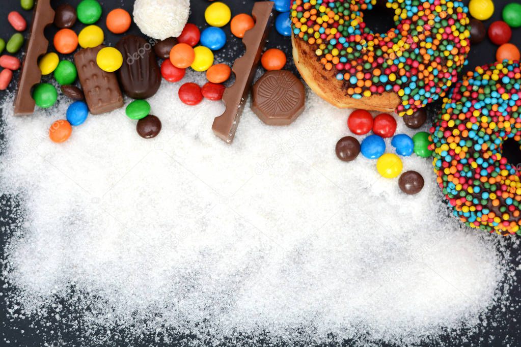 Various sweets and sugar powder as background, with no text