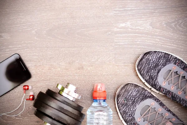 Equipamento de esporte ou fitness com sapatos esportivos, haltere e garrafa de água no fundo escuro — Fotografia de Stock