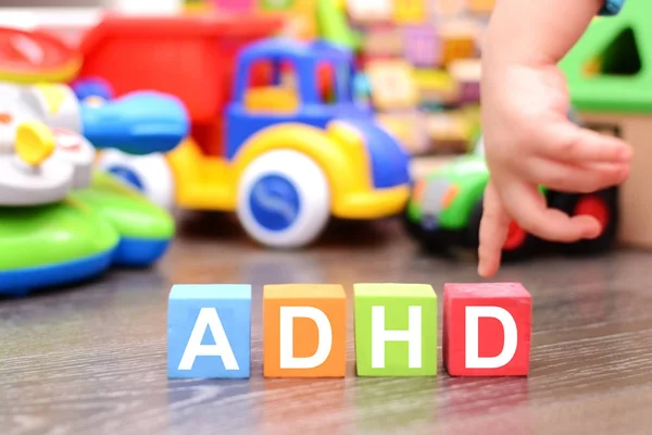 Transtorno de Déficit de Atenção Hiperatividade ou conceito ADHD com a mão da criança tocando cubos coloridos contra brinquedos — Fotografia de Stock