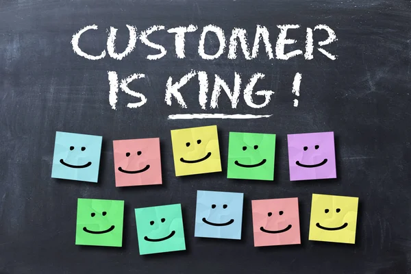 El cliente es el rey de texto en pizarra con caras sonrientes en notas adhesivas de colores — Foto de Stock