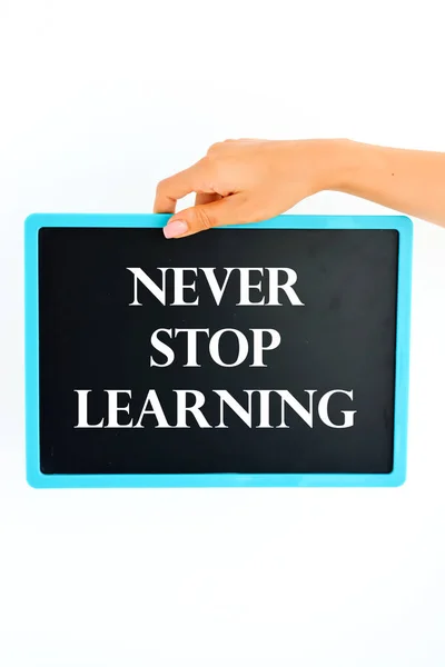 Never stop learning written on small blackboard in woman hand — Stock Photo, Image