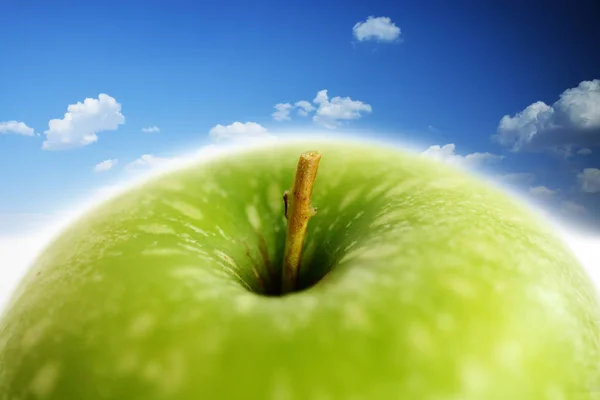 Green apple against blue sky, composite image — Stock Photo, Image