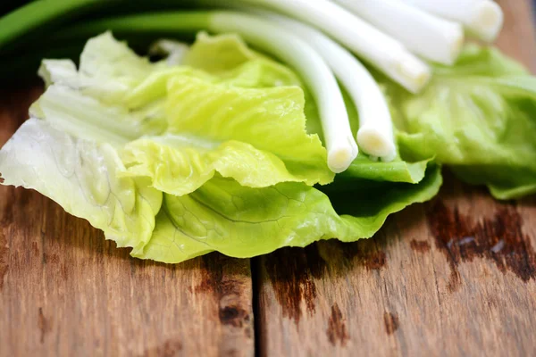 Healthy and natural ingredients, fresh lettuce leaves and green onion on wooden background — Stock Photo, Image