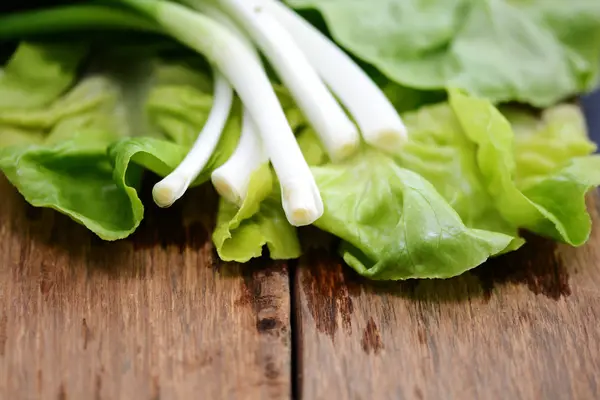 Zdravé a přírodní ingredience, čerstvý salát listy a cibule na dřevěné pozadí — Stock fotografie