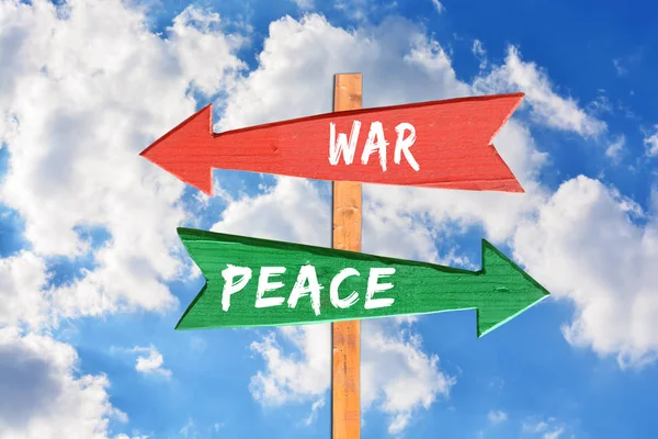 Kriget mot fred på trä directional suck mot blå himmel — Stockfoto