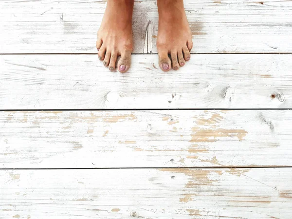 Young woman feet on wooden floor as background