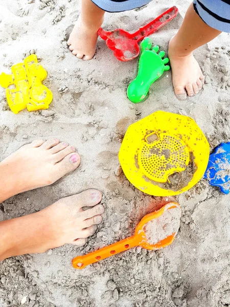 Happy family feet on the beach playing with toys in sand