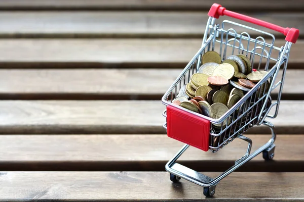 Carro de compras lleno de dinero sobre fondo de madera sugiriendo precios crecientes —  Fotos de Stock