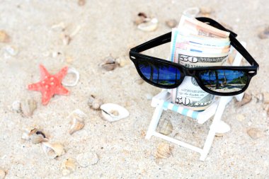 Tatil para kavramı - banknotlar Bununla birlikte güneş gözlüklü bir plaj sandalye ve kum arka planda