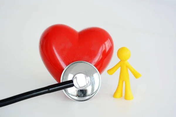 Concepto de corazón saludable con estetoscopio y corazón rojo cerca de una miniatura humana —  Fotos de Stock