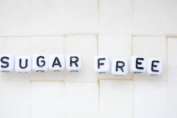 Cukr volný text napsaný s korálky plastové dopis na pozadí kostky cukru — Stock fotografie