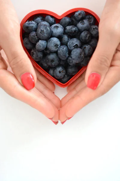 Loving healthy fruits, woman hands with blueberries in red heart — Stock Photo, Image