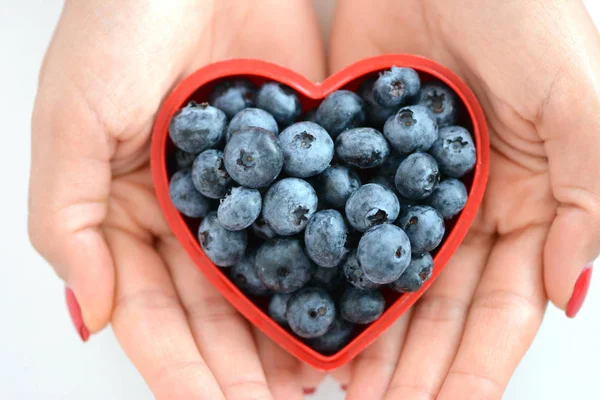 Loving healthy fruits, woman hands with blueberries in red heart — Stock Photo, Image