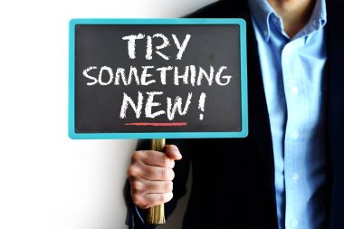 Yeni bir şey tavsiye bir işadamı tarafından düzenlenen küçük kara tahta üzerinde el yazısı deneyin