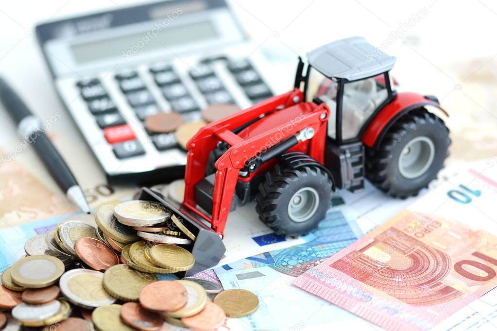 Analyzing financial result in agriculture with tractor pushing a lot of money near office tools