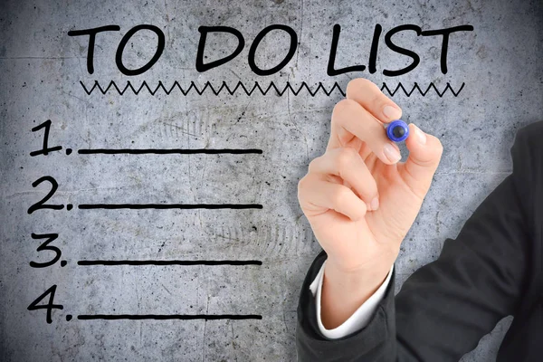 Businesswoman drawing up a to do list on concrete background, new year strategy concept — Stock Photo, Image