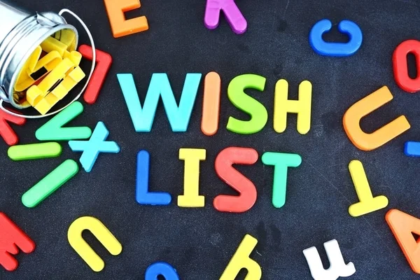 Wunschzettelkonzept mit bunten Buchstaben auf der Tafel, die aus einem metallischen Eimer strömen — Stockfoto