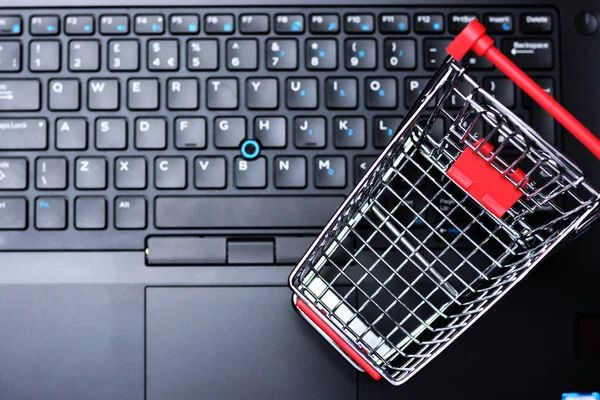 在线购买和电子商务概念与空购物车作为符号在笔记本电脑键盘 — 图库照片