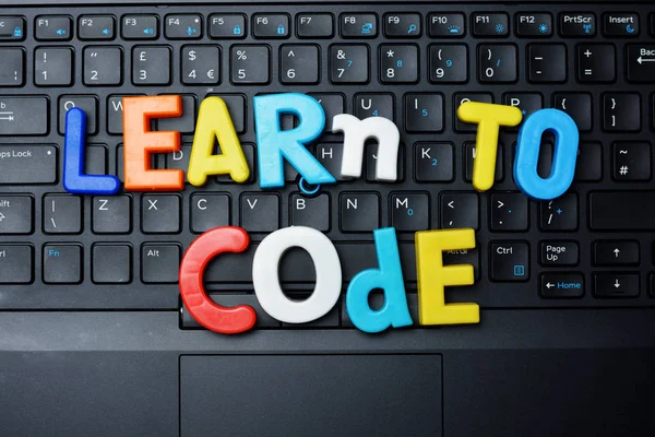 ノートブックのキーボード上のカラフルな文字からコード アドバイスすることを学ぶ教育技術のコンセプト — ストック写真