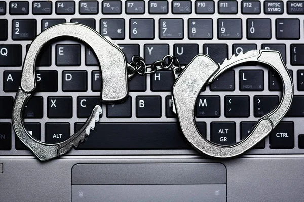 Handcuffs and computer keyboard suggesting hacker concept or internet fraud