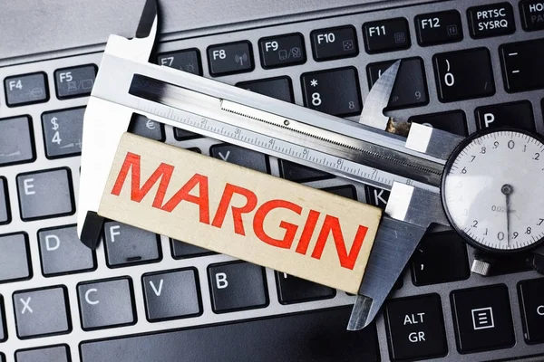 Measure margin of profit concept with caliper tool on computer keyboard